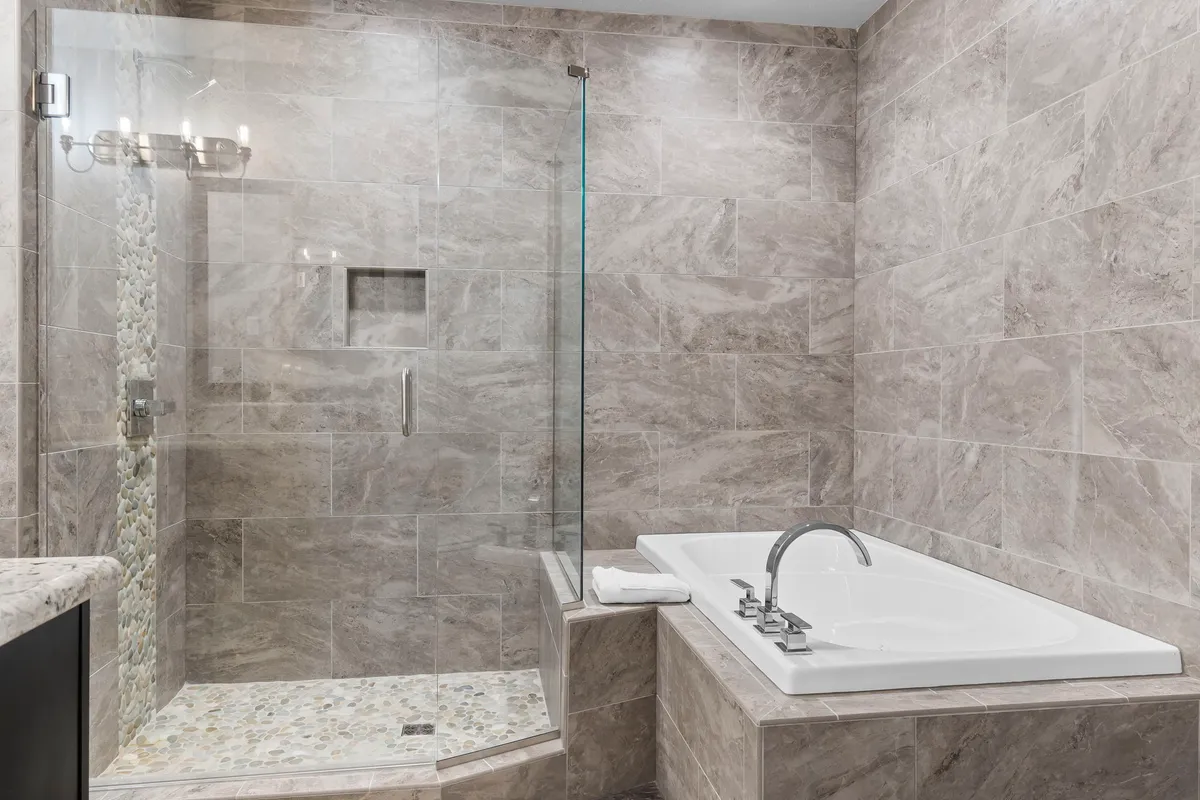 A luxurious bathroom featuring a freestanding bathtub, glass-enclosed shower, and textured tiles. The space feels tranquil and spa-like, ideal for unwinding after a day of adventure.