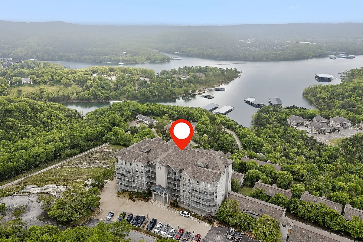 A peaceful scene featuring the condo building set against a backdrop of water and greenery. This angle showcases the building’s relationship to the lake and the lush landscape, emphasizing tranquility and outdoor enjoyment.